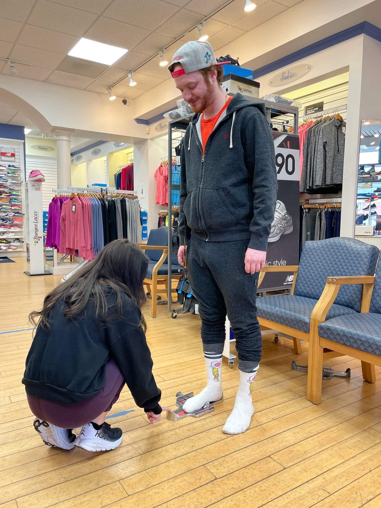 woman measuring both feet of man to check his size