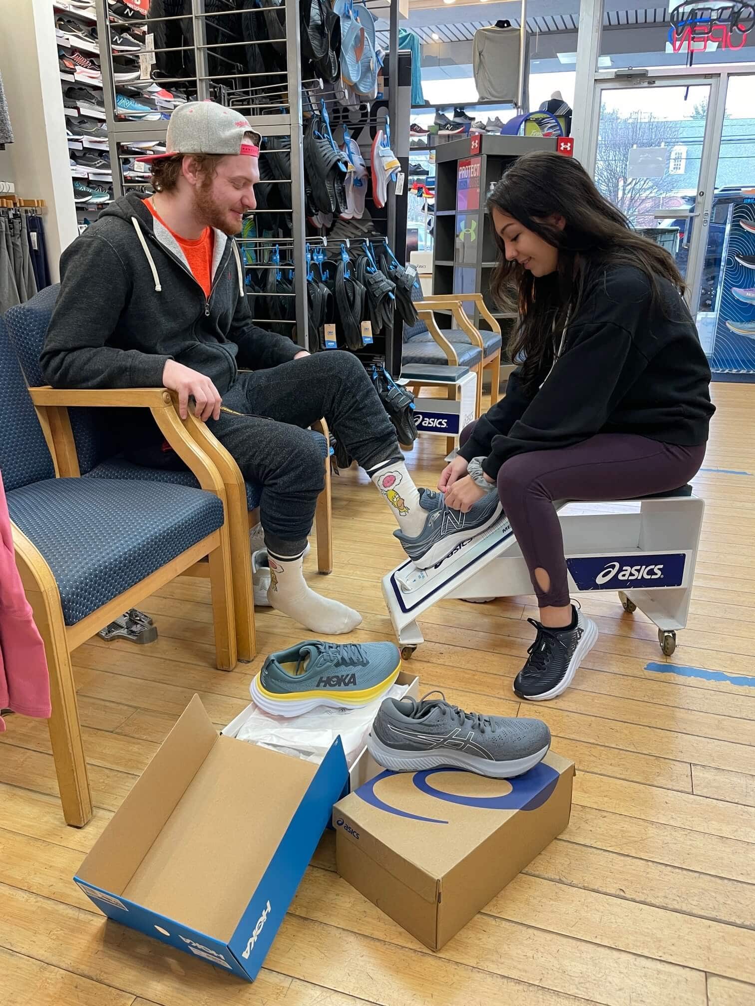 man being fitted with sneakers by woman
